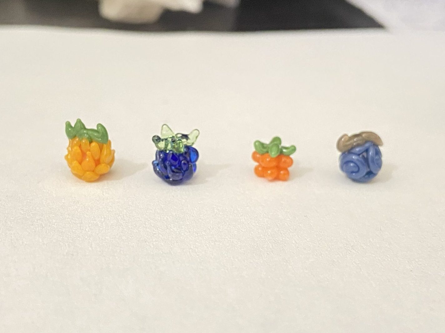 Four One Piece Devil Fruit inspired borosilicate glass bead art sculptures